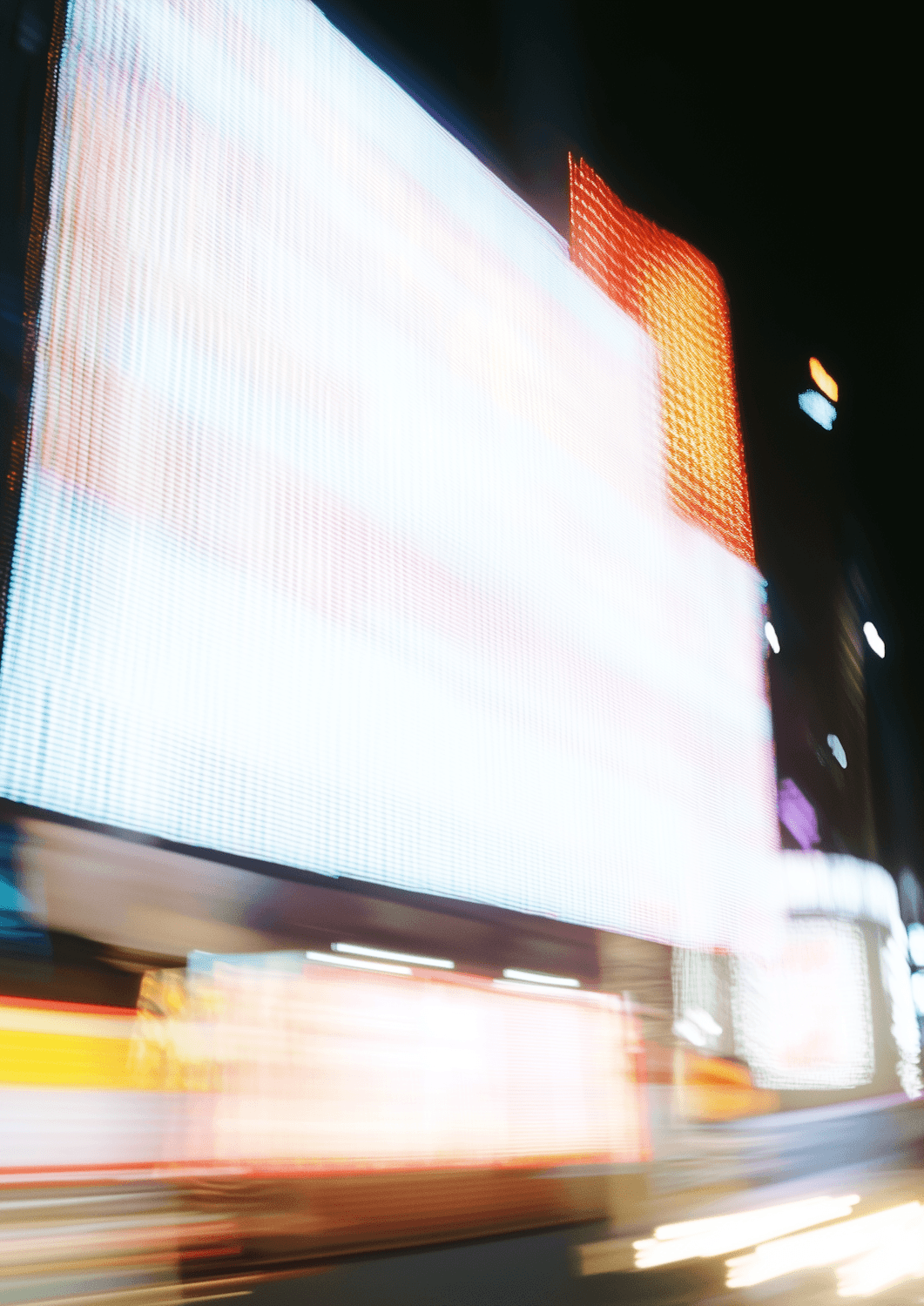 Blurred neon billboards and streaks of city light at night